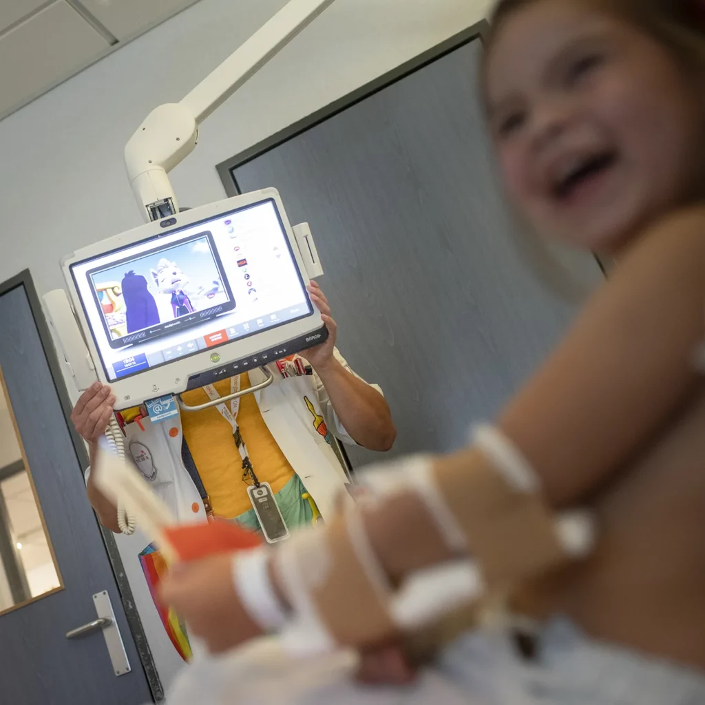 Una niña hospitalizada se ríe durante la visita de los Doctores Sonrisa de la Fundación Theodora