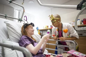 Doctora Sonrisa de la Fundación Theodora ríe con una paciente sentada en su cama