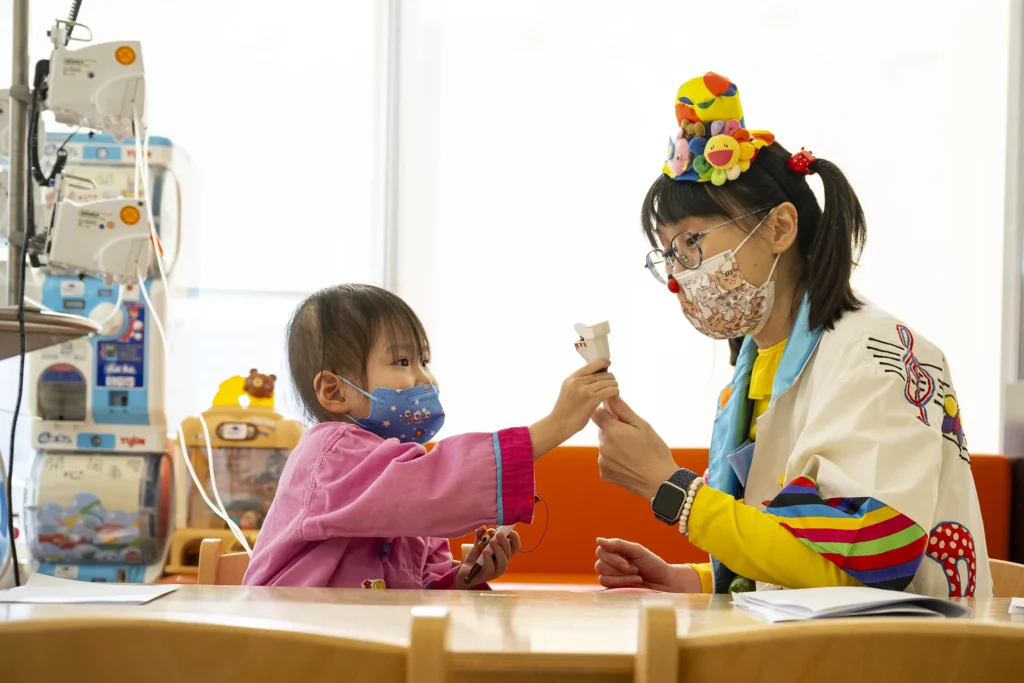 Una Doctora Sonrisa de la Fundación Theodora juega con una niña pequeña en una sala del hospital