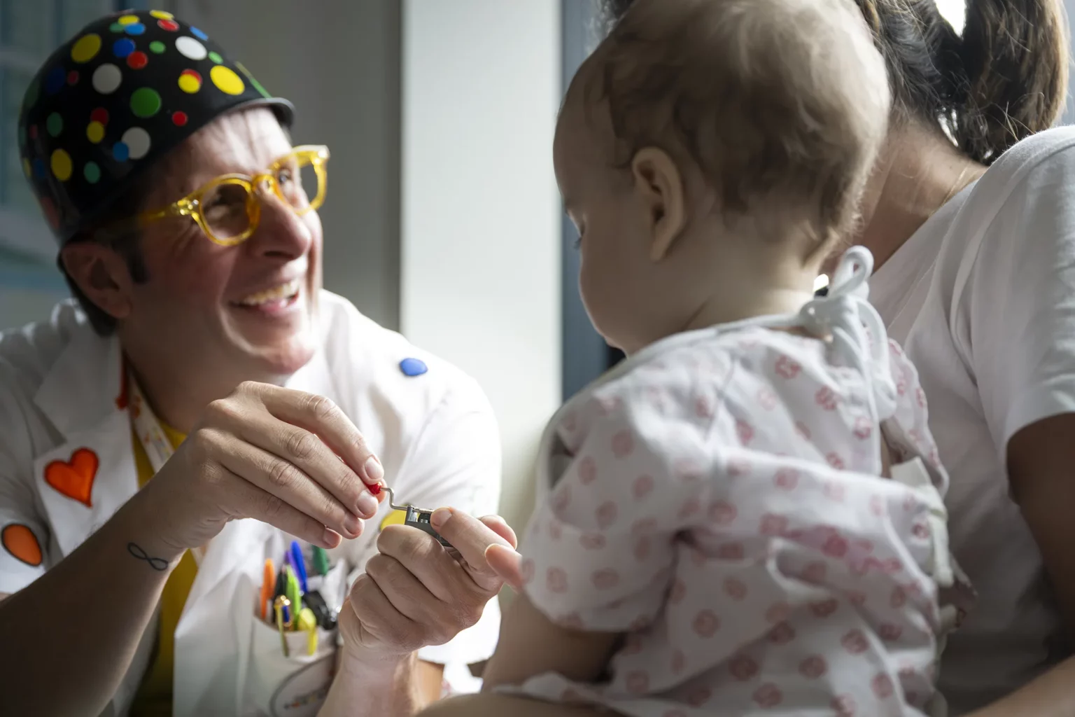 Doctor Sonrisa de la Fundación Theodora sonríe a un bebé en brazos de un familiar